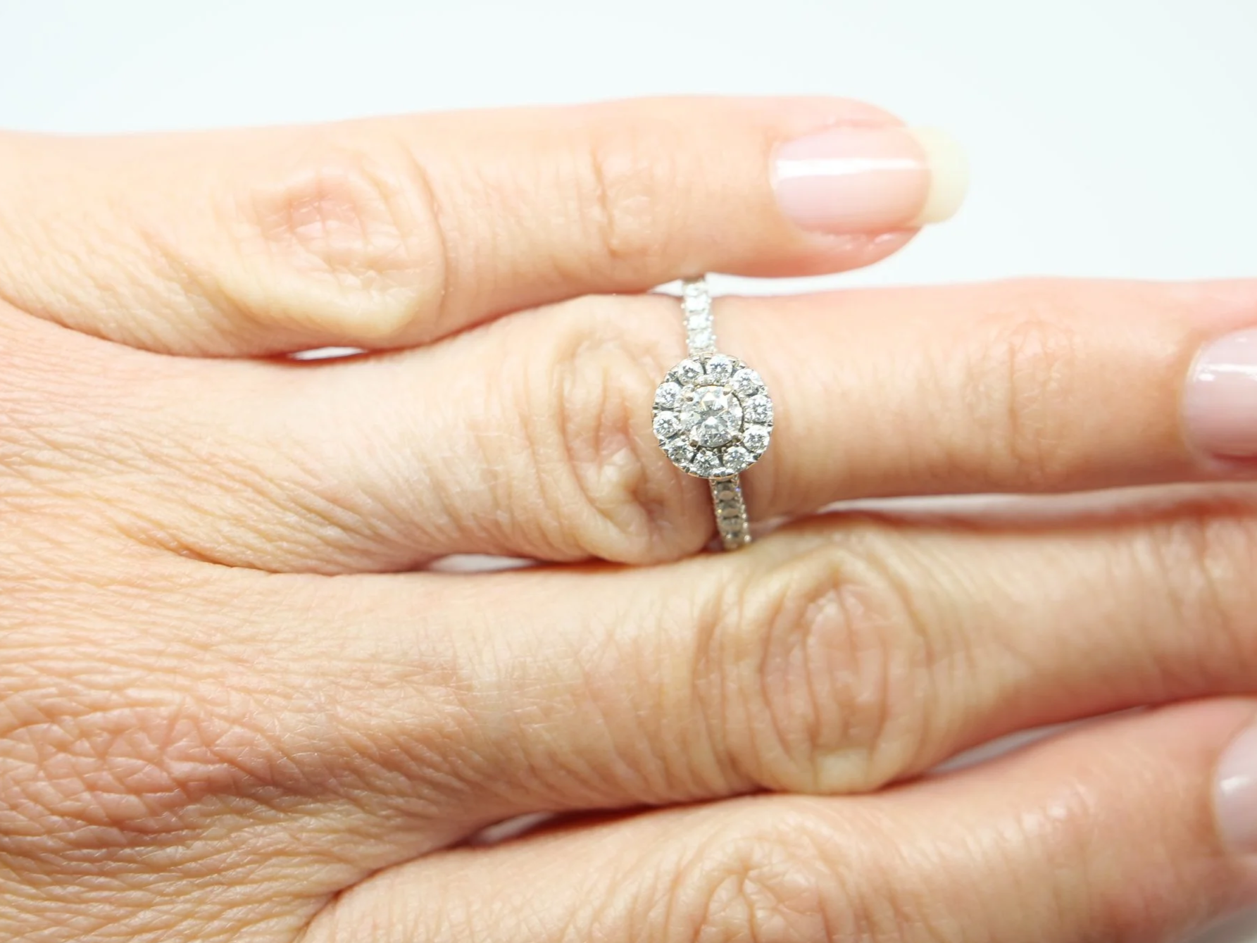 14ct white gold diamond halo ring set with a round brilliant cut diamond at the centre surrounded by a pavé-set halo of smaller diamonds