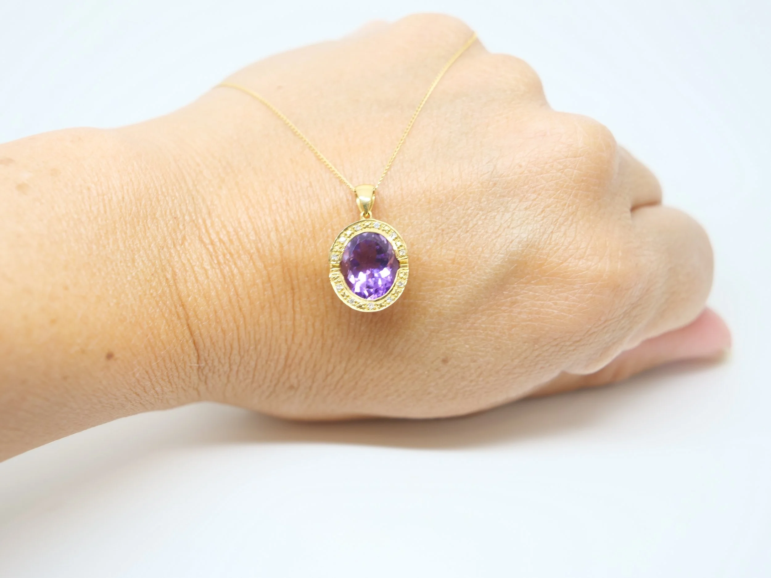 An 18ct gold pendant necklace with a large oval amethyst of approximately 4.5ct in a diamond-set halo.