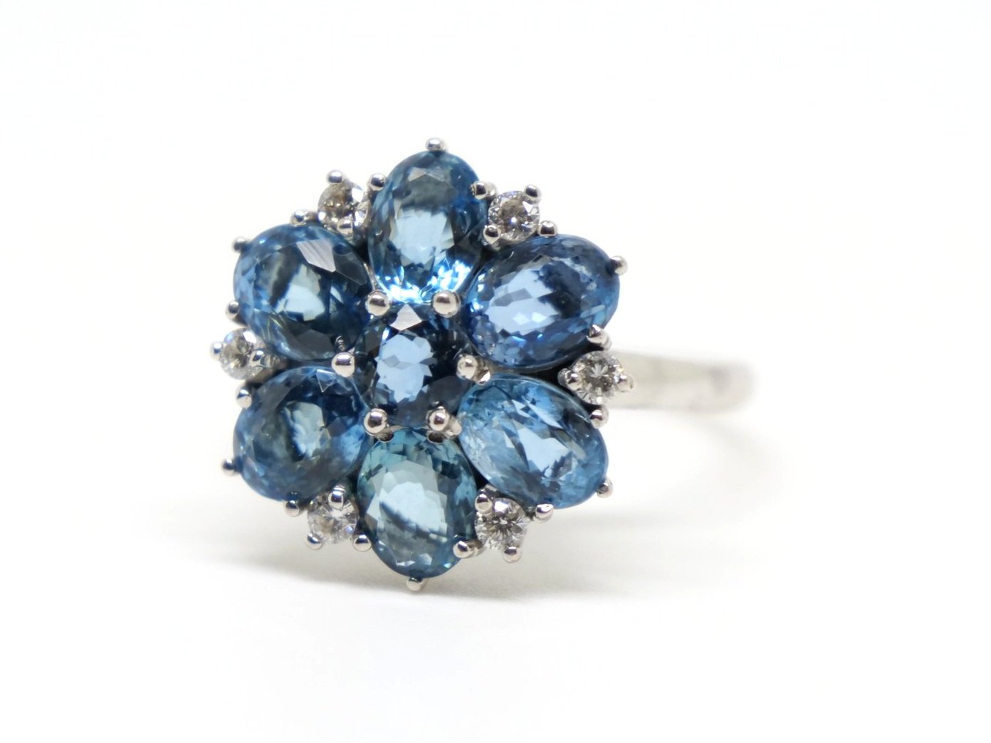 Very unusual 18ct gold aquamarine and diamond cocktail ring in a wonderful floral design. The ring is set with six oval cut mid blue aquamarines, with a round cut centre. Diamond accents.