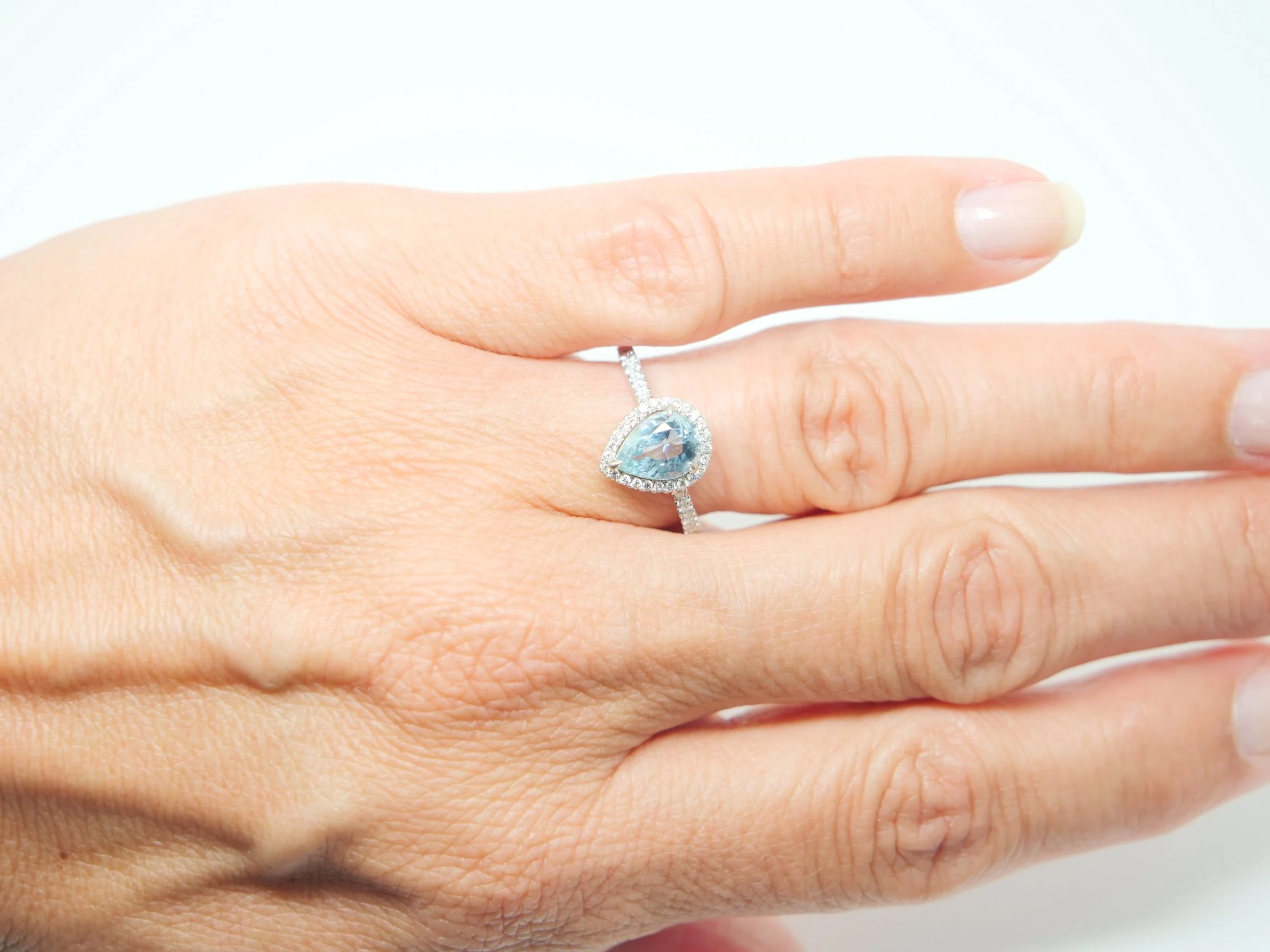 18ct white gold aquamarine and diamond halo ring, set with a pear cut aquamarine at the centre