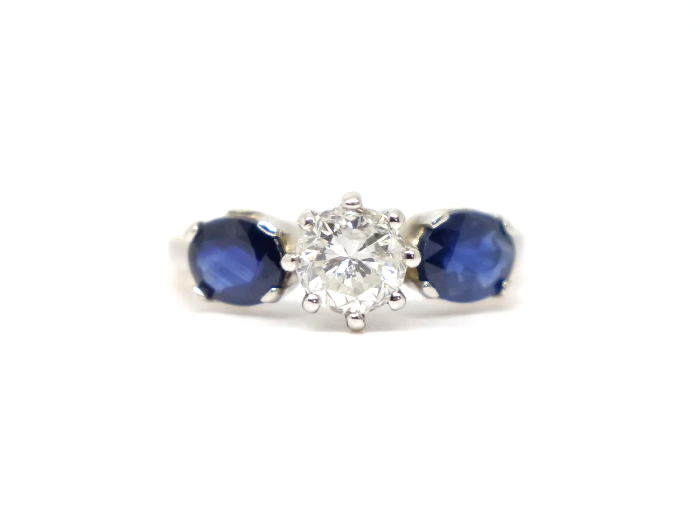 unusual vintage three stone ring in 18ct white gold with a round old cut diamond of approximately 1 carat at the centre, flanked by two oval cut sapphires of approximately 1.4 carats in total.