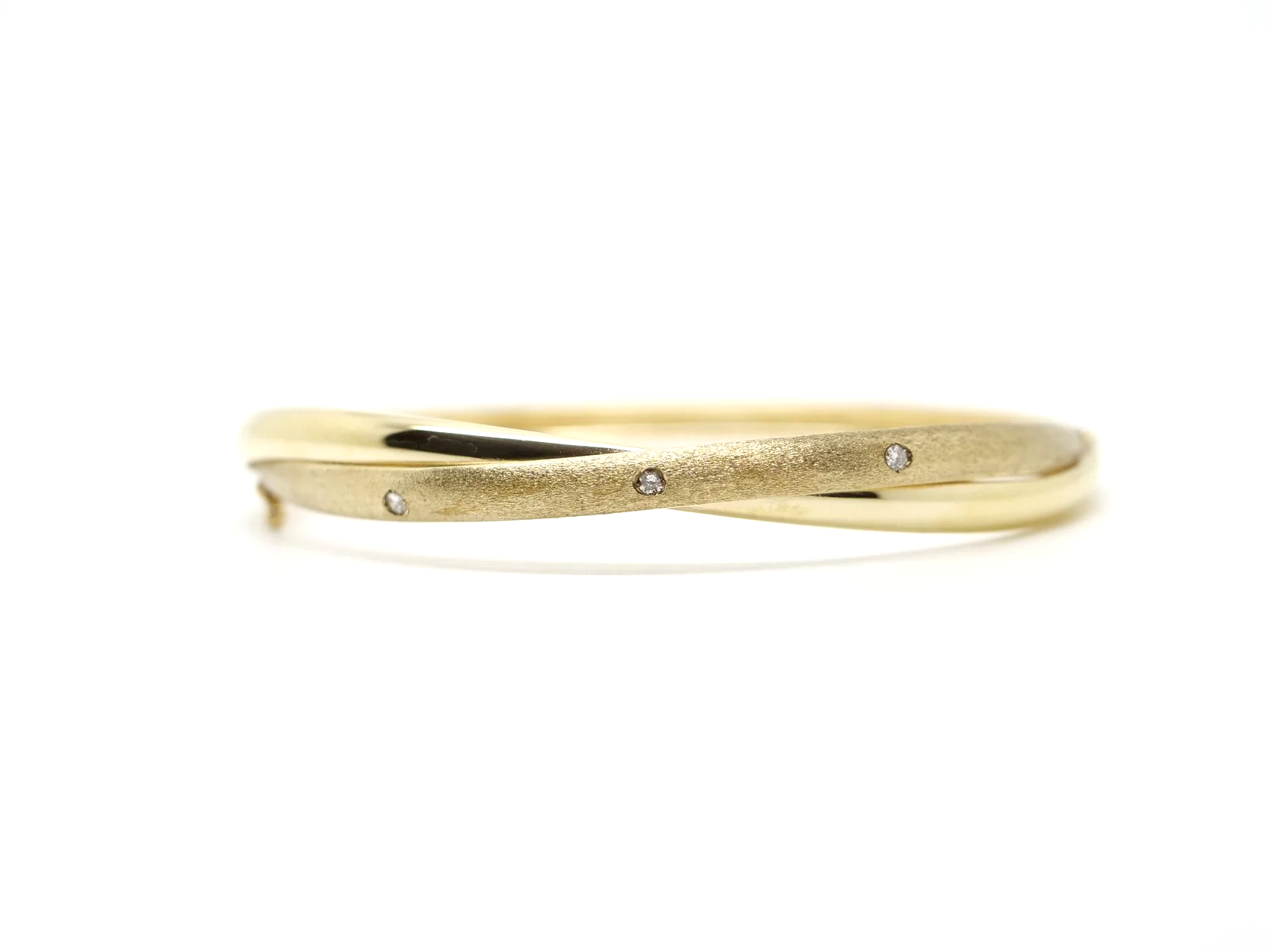 Unusual 9ct gold twist design bangle, with one matte gold band and one polished gold band. Small diamonds inset into the band.