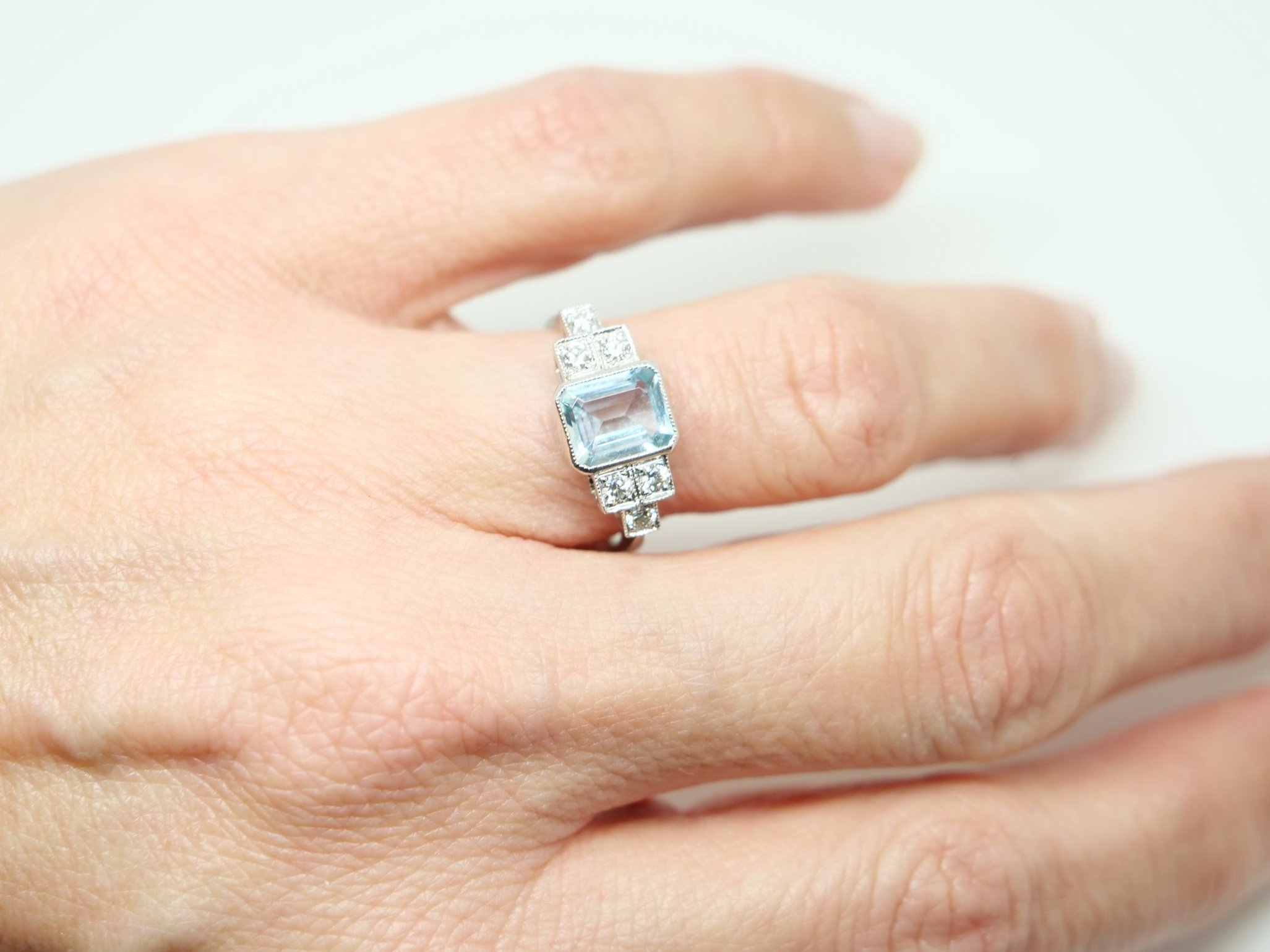 Beautiful Art Deco style platinum aquamarine and diamond ring, set with a central emerald cut aquamarine, with three diamonds set in a step design to each shoulder.