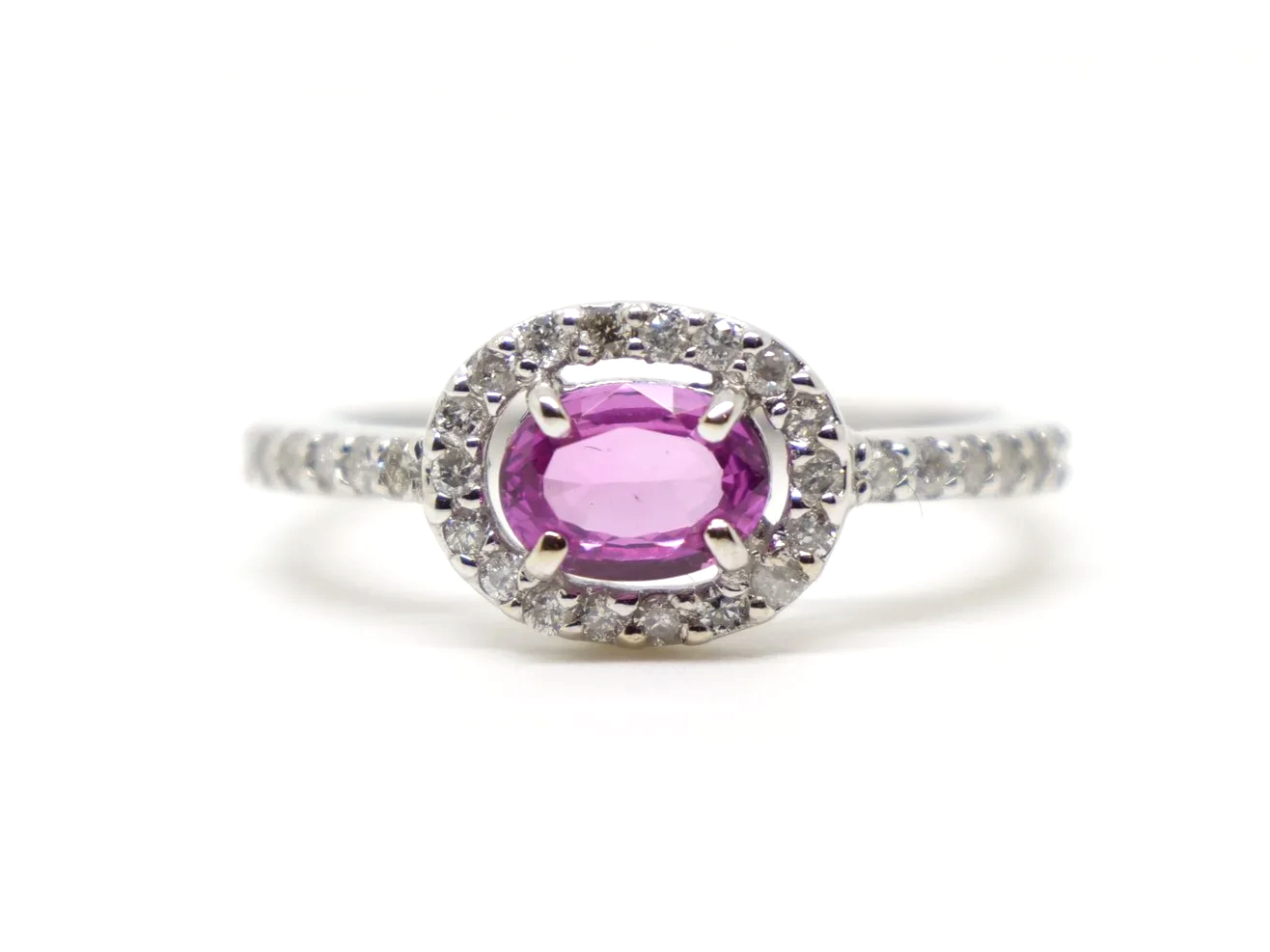 Very sparkly contemporary 18ct gold pink sapphire and diamond ring, set with an oval cut east-west pink sapphire, with a diamond halo. Further diamonds to the shoulders.