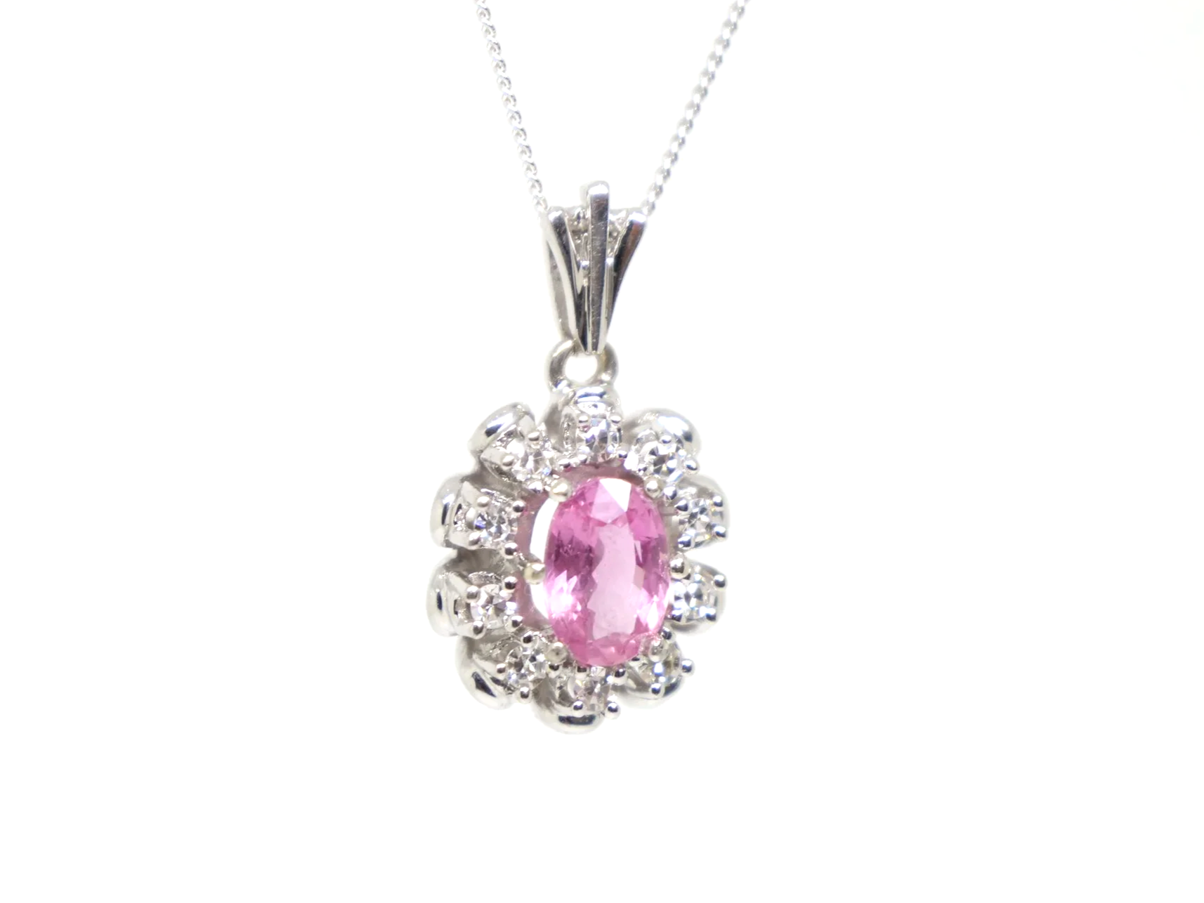 vintage 14ct white gold pink sapphire and diamond cluster pendant, set with a striking oval cut pink sapphire and surrounded by diamonds.