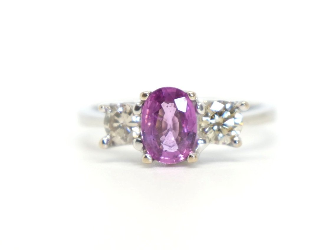 Stunning 18ct gold pink sapphire and diamond trilogy ring, set with a 1ct oval cut pink sapphire with a diamond to each side.