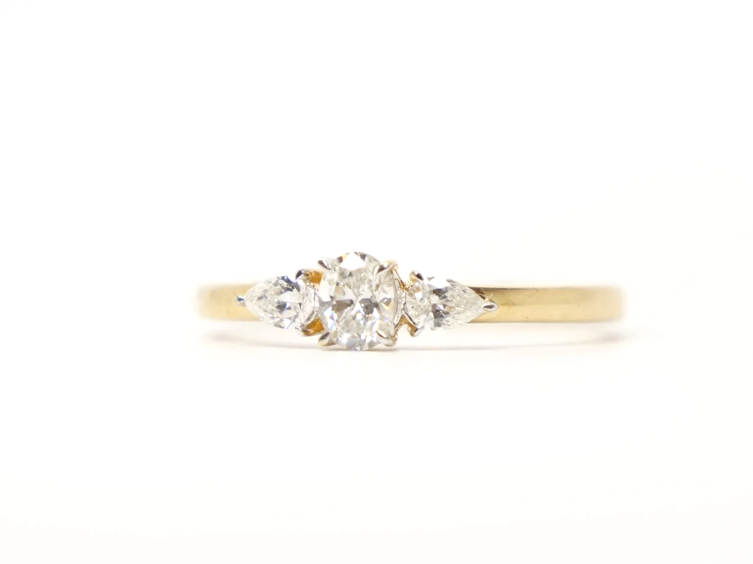 18ct yellow gold three-stone diamond ring, set with an oval brilliant-cut diamond at the centre, with a pear-cut diamond to each side