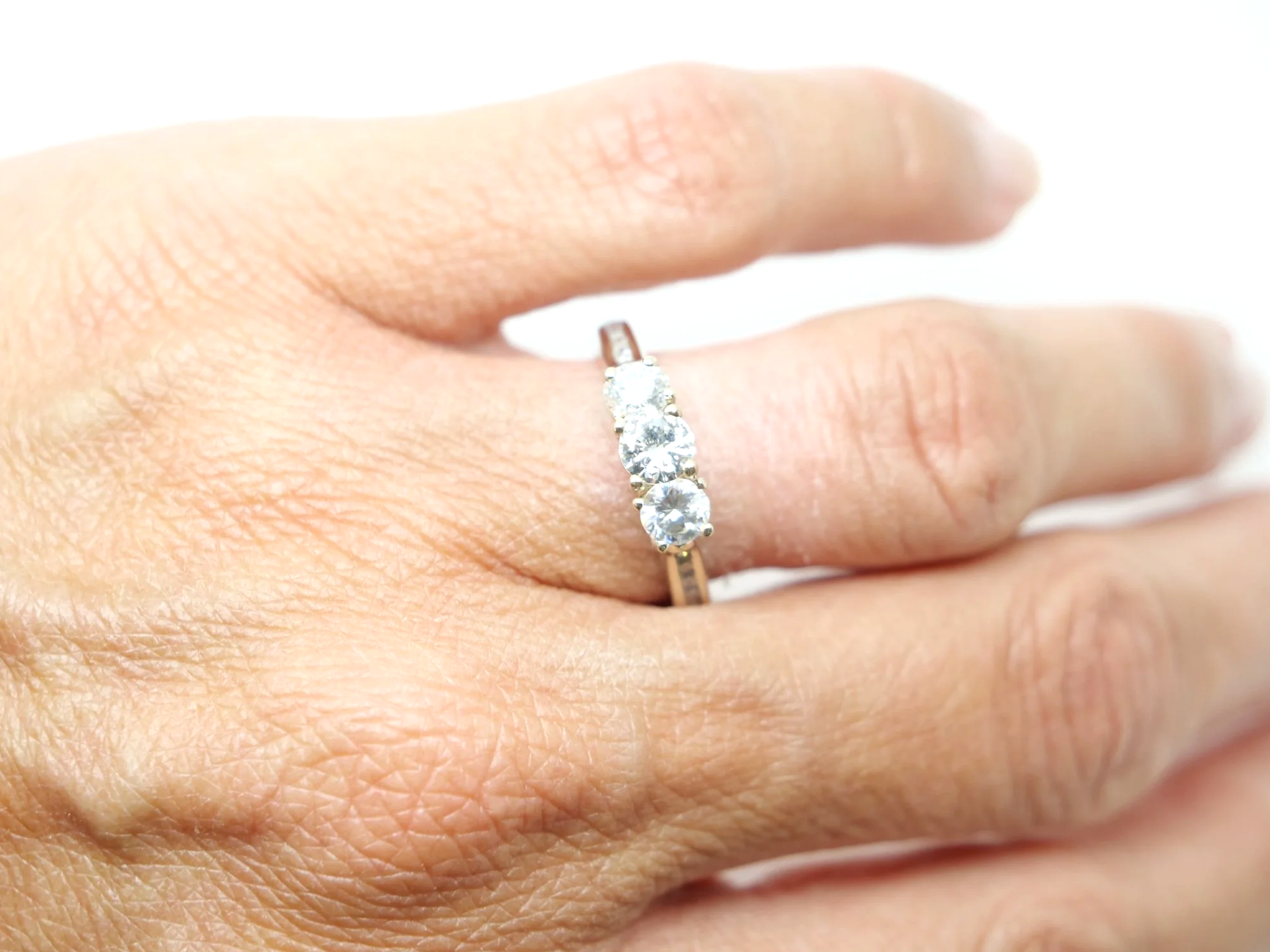 Very pretty 18ct gold diamond three stone ring, set with three brilliant cut diamonds, with further diamonds set into each shoulder. Total diamond weight approximately 1ct.