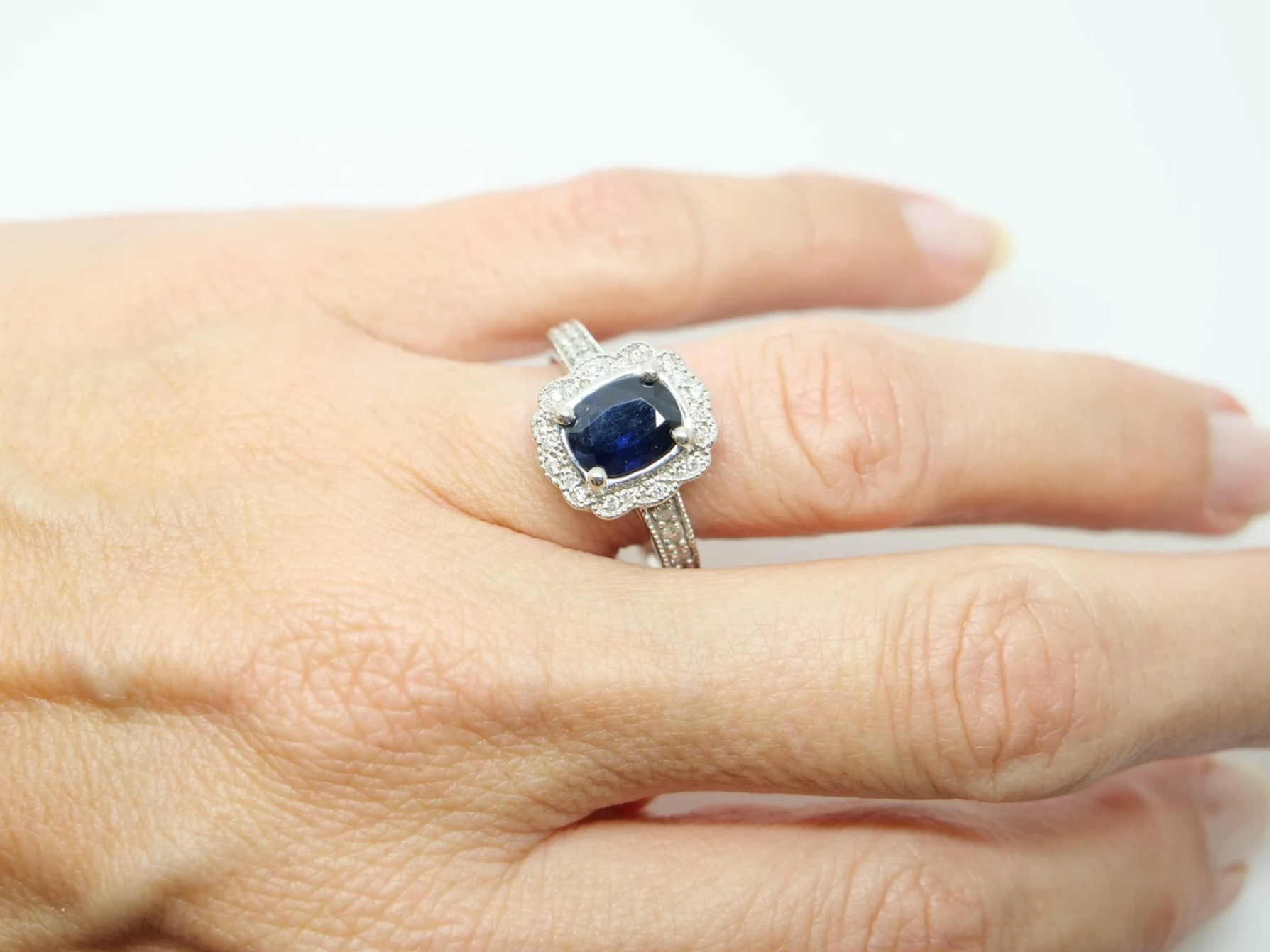 Lovely vintage design platinum ring, set with a large oval cut sapphire and surrounded by diamonds. Further diamonds set into each shoulder.