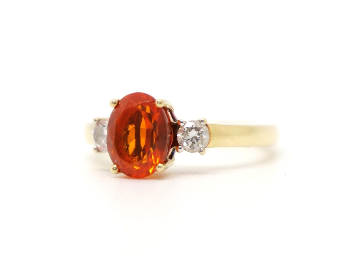 Unusual 18ct gold fire opal and diamond trilogy ring, set with a large oval cut fire opal and with a brilliant cut diamond to each shoulder.