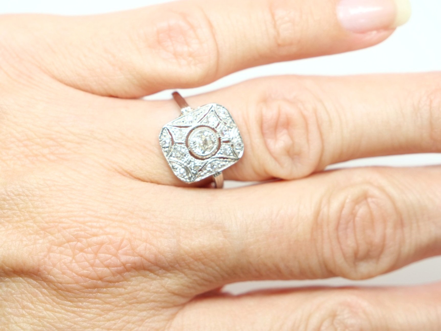 Very pretty platinum and diamond ring in Art Deco style, set with a central old cut diamond and with further diamonds set into the lovely geometrical design.