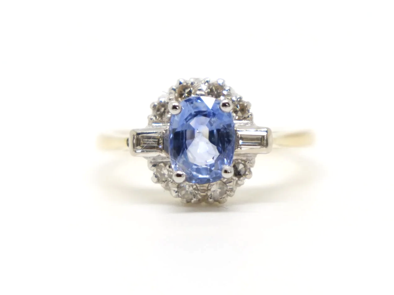 Stunning 18ct gold sapphire and diamond ring, set with an oval light blue sapphire and surrounded by diamonds, with a baguette diamond to each shoulder.