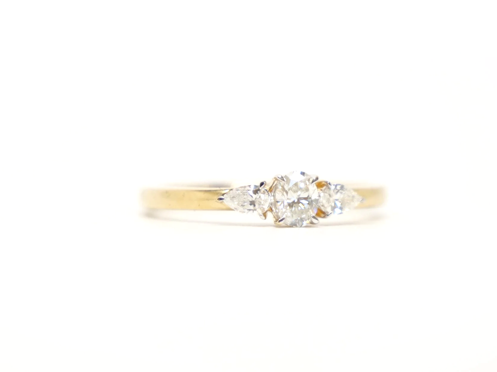 18ct yellow gold three-stone diamond ring, set with an oval brilliant-cut diamond at the centre, with a pear-cut diamond to each side