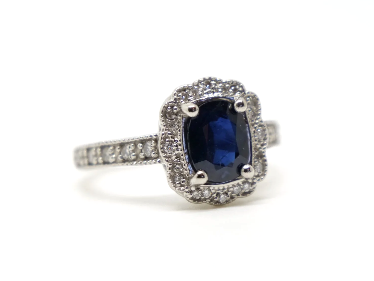 Lovely vintage design platinum ring, set with a large oval cut sapphire and surrounded by diamonds. Further diamonds set into each shoulder.