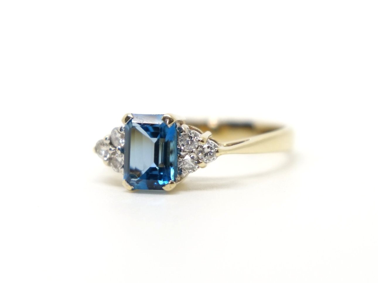 Very pretty 9ct gold blue topaz and diamond ring, set with an emerald cut blue topaz, with three diamonds to each side.