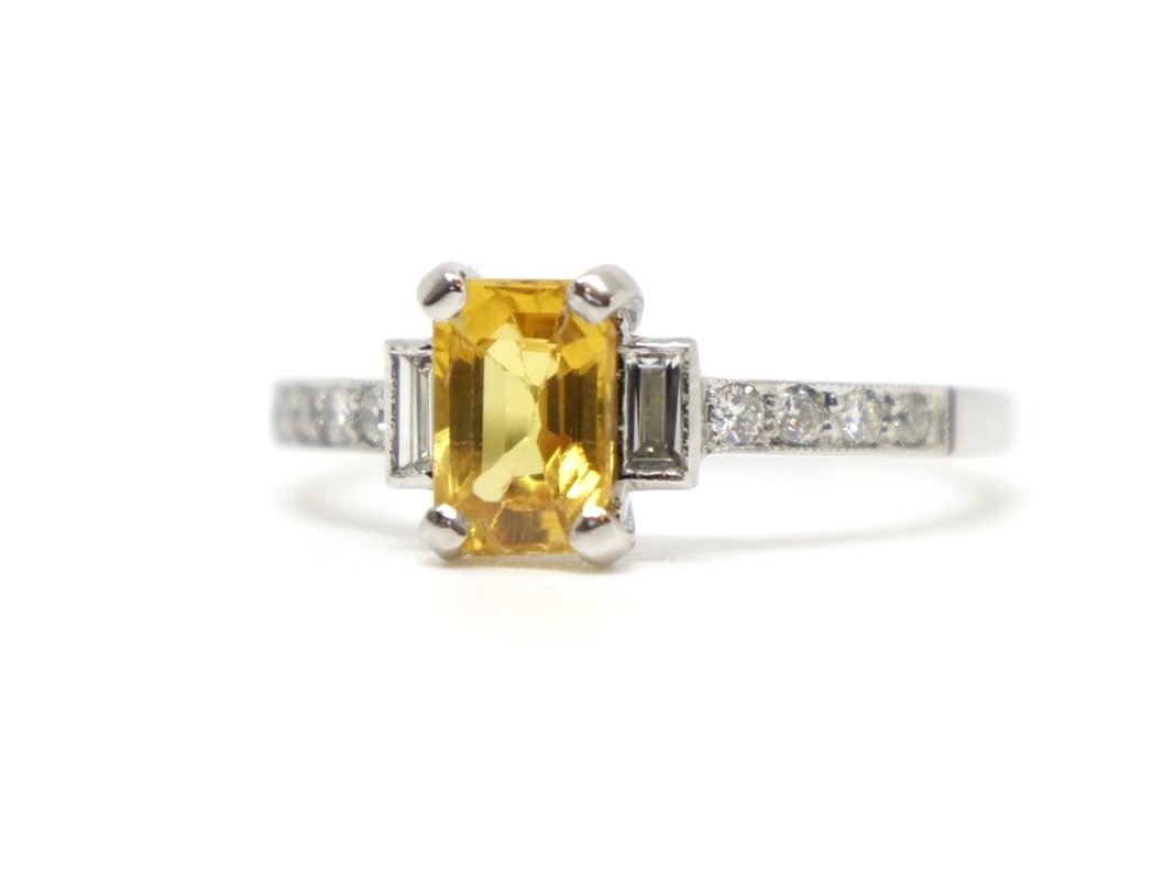 Beautiful vintage style platinum yellow sapphire and diamond ring, set with a 1ct emerald cut sapphire with a baguette cut diamond to each side. Further diamonds to each shoulder.
