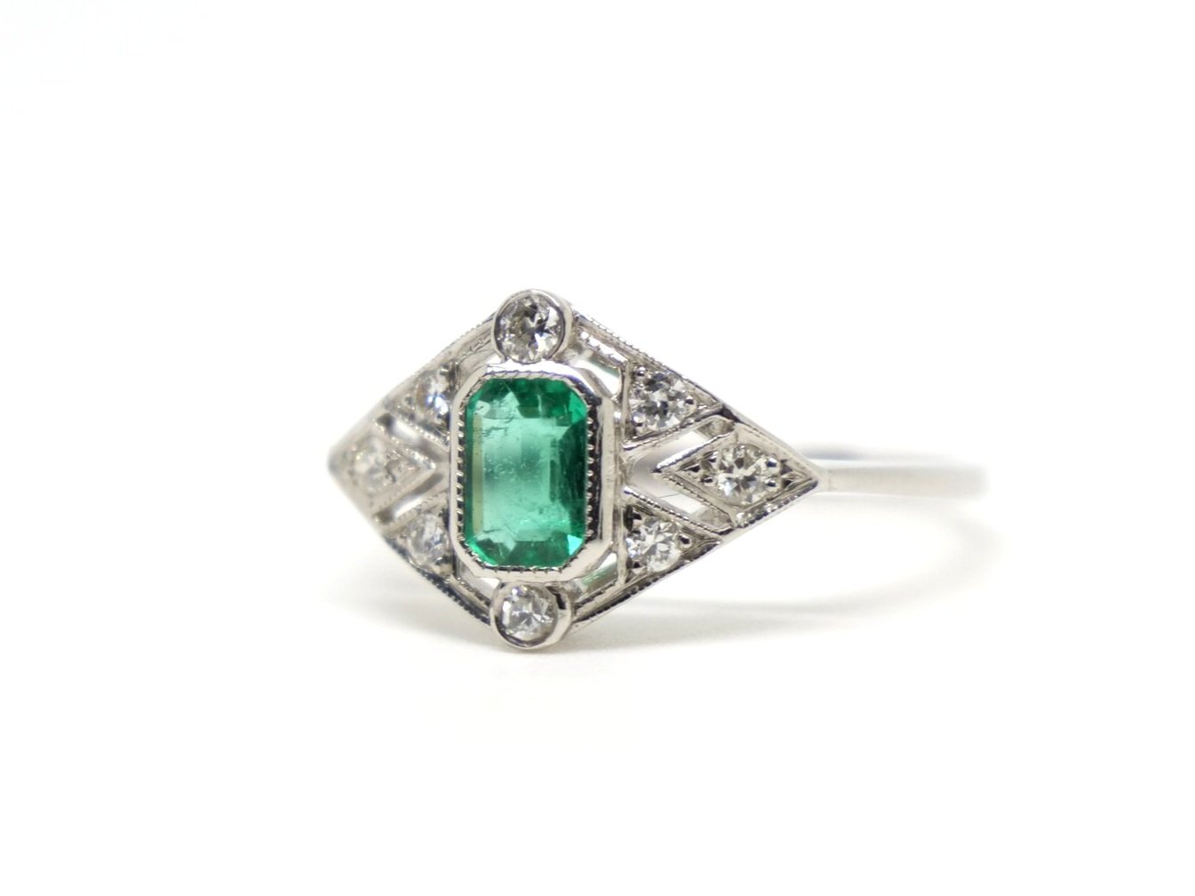 Very pretty Art Deco style platinum ring, set with an emerald cut emerald and set with diamonds in this lovely geometric design.