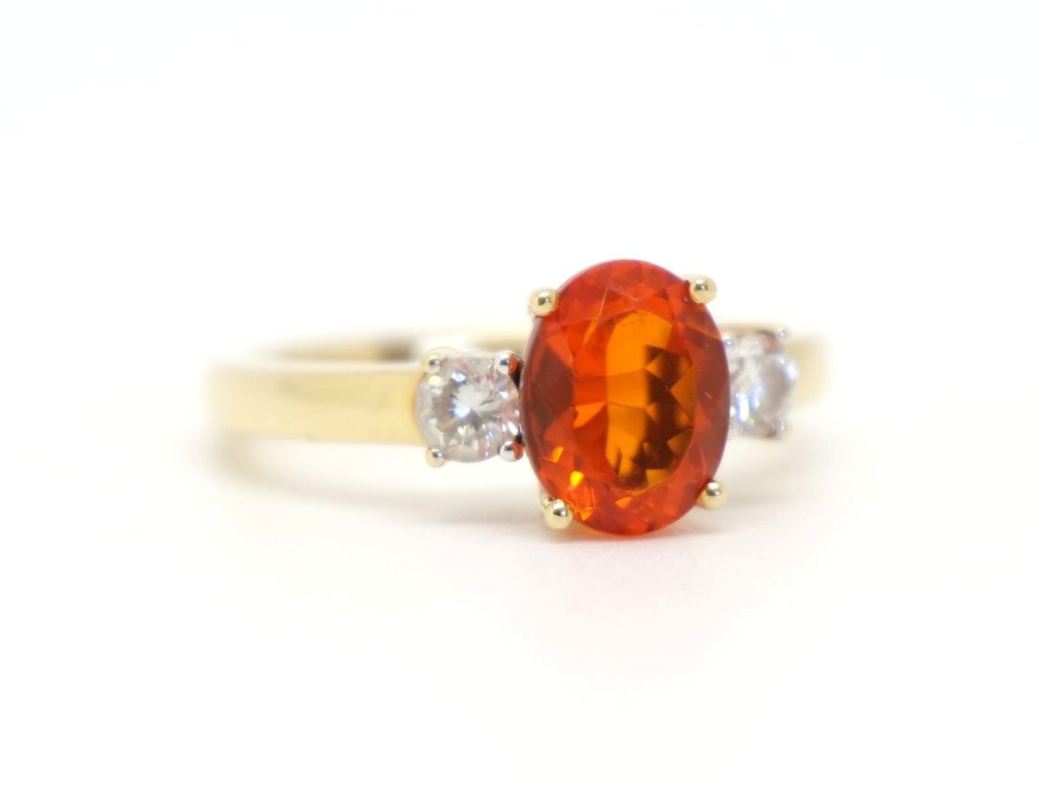 Unusual 18ct gold fire opal and diamond trilogy ring, set with a large oval cut fire opal and with a brilliant cut diamond to each shoulder.
