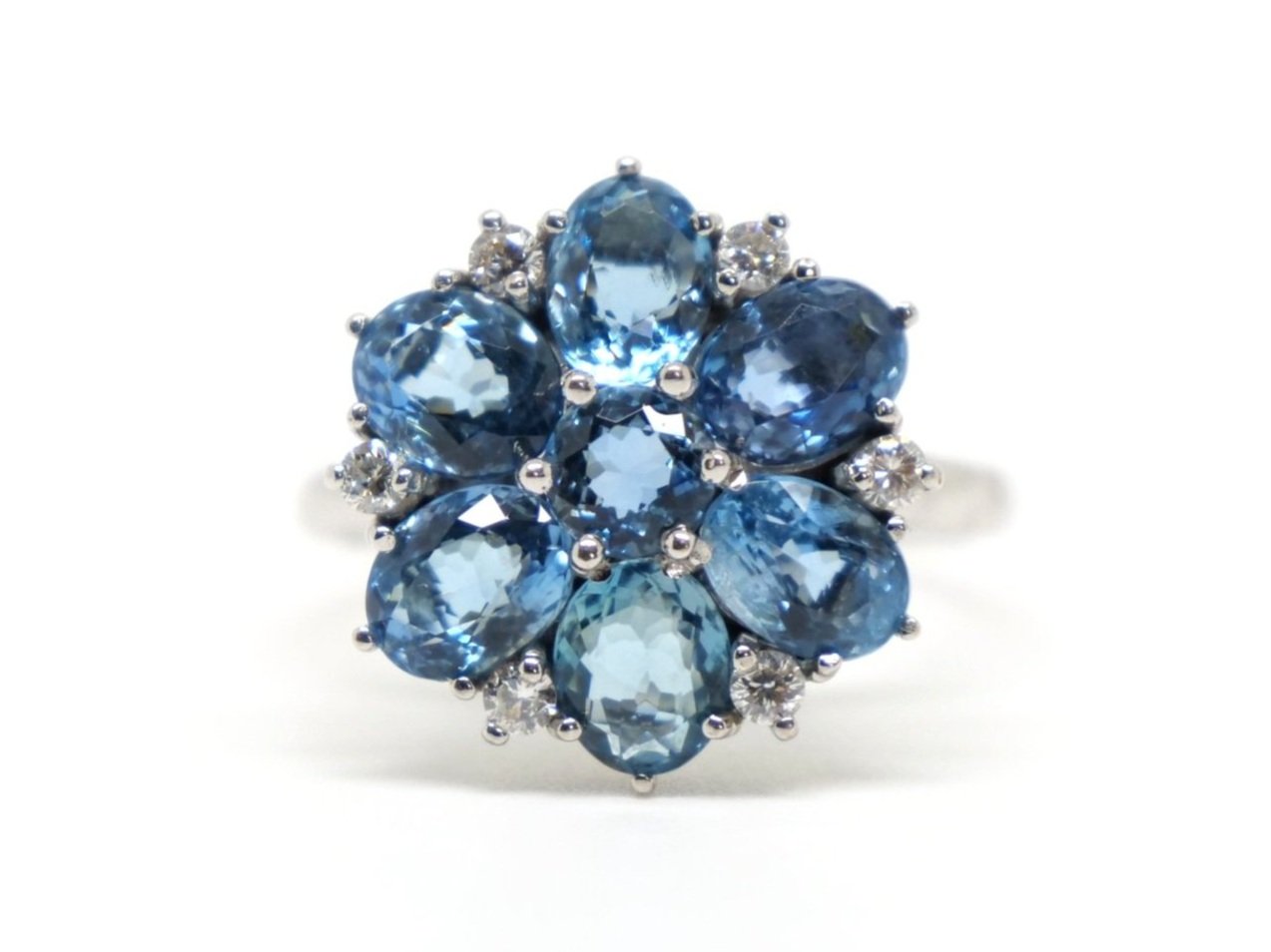 Very unusual 18ct gold aquamarine and diamond cocktail ring in a wonderful floral design. The ring is set with six oval cut mid blue aquamarines, with a round cut centre. Diamond accents.