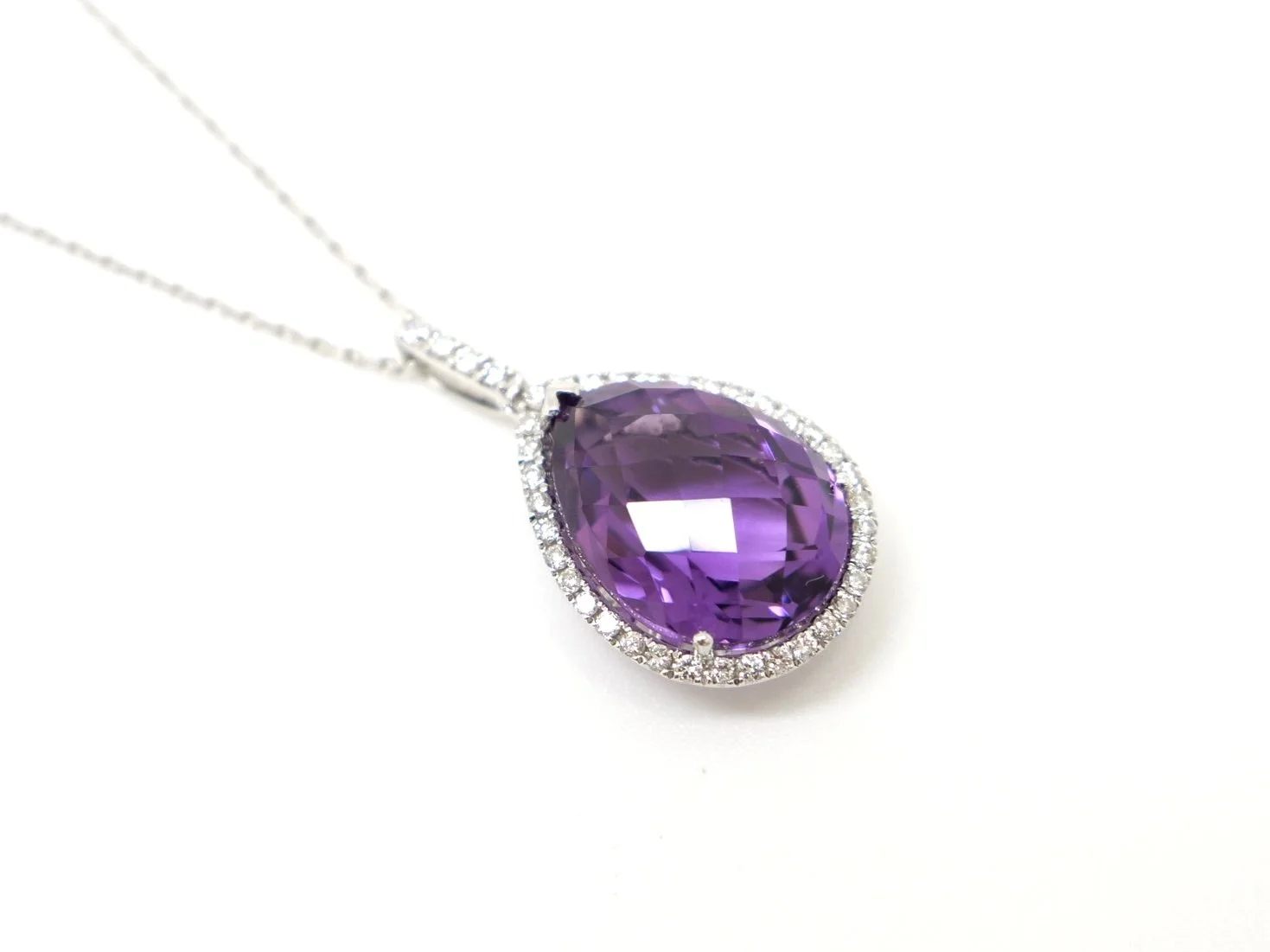 Very pretty 14ct gold amethyst and diamond pendant, set with a large pear cut amethyst and surrounded by diamonds. Further diamonds to bale. With 9ct white gold chain.
