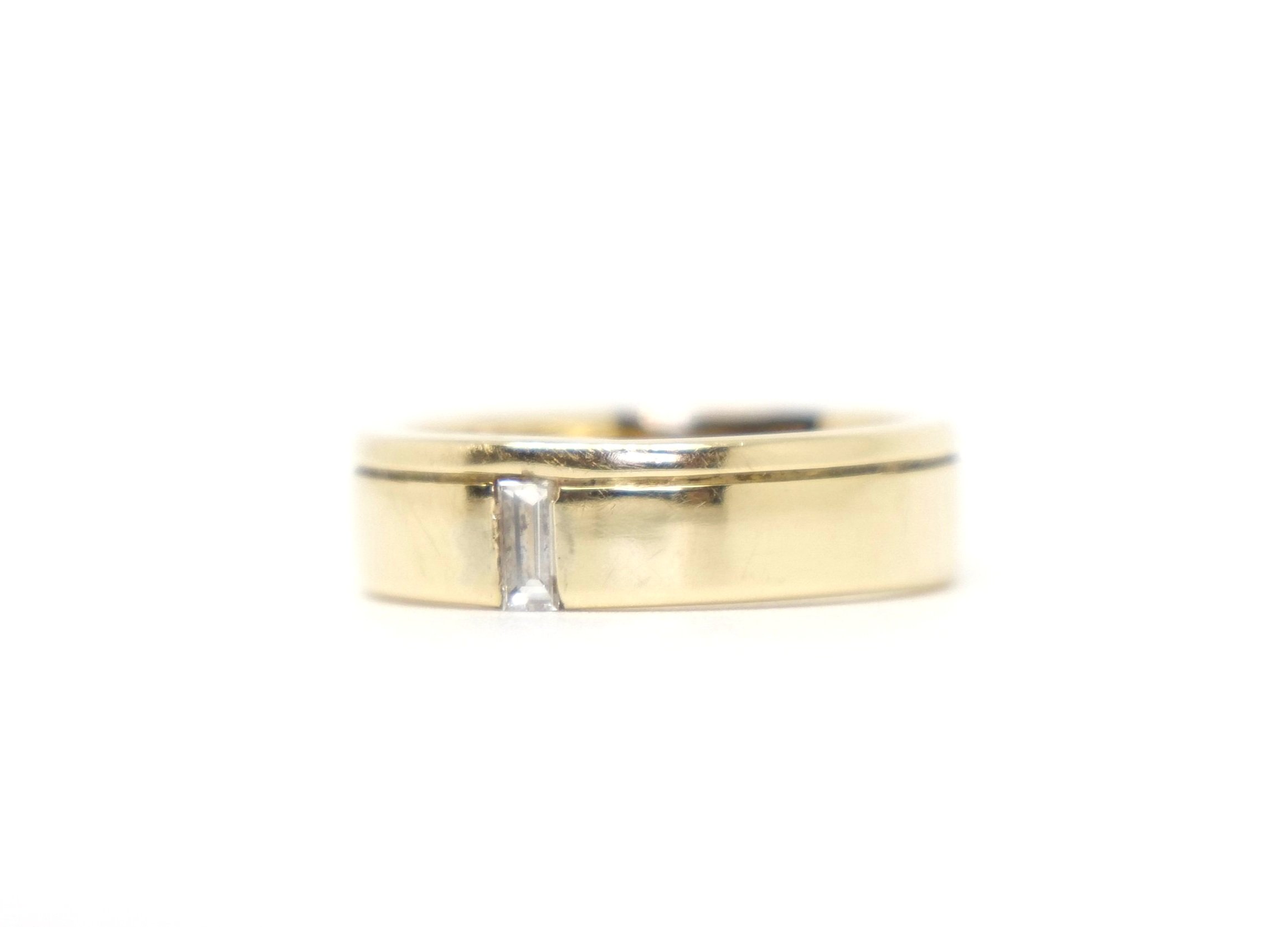 Contemporary style 14ct gold band ring, with a 5mm wide band and set with a single elegant baguette cut diamond.