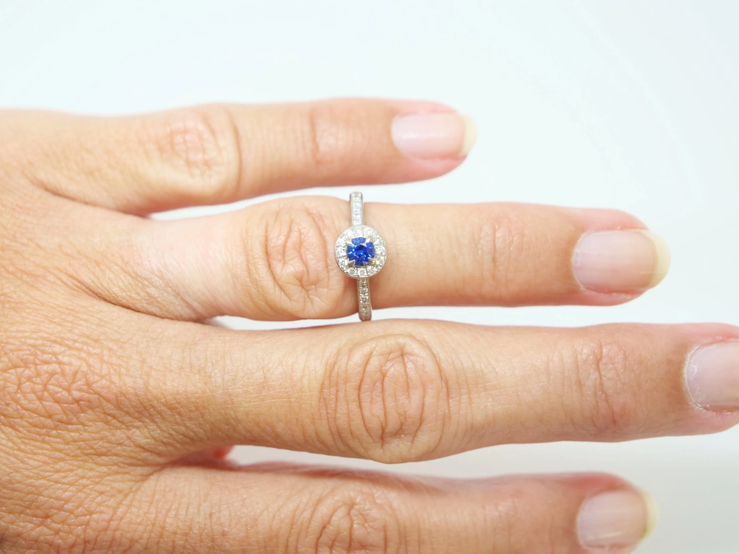 Lovely sapphire and diamond halo ring in 18ct white gold, set with a round-cut blue sapphire of approximately 0.35ct, and encircled by a halo of brilliant-cut diamonds