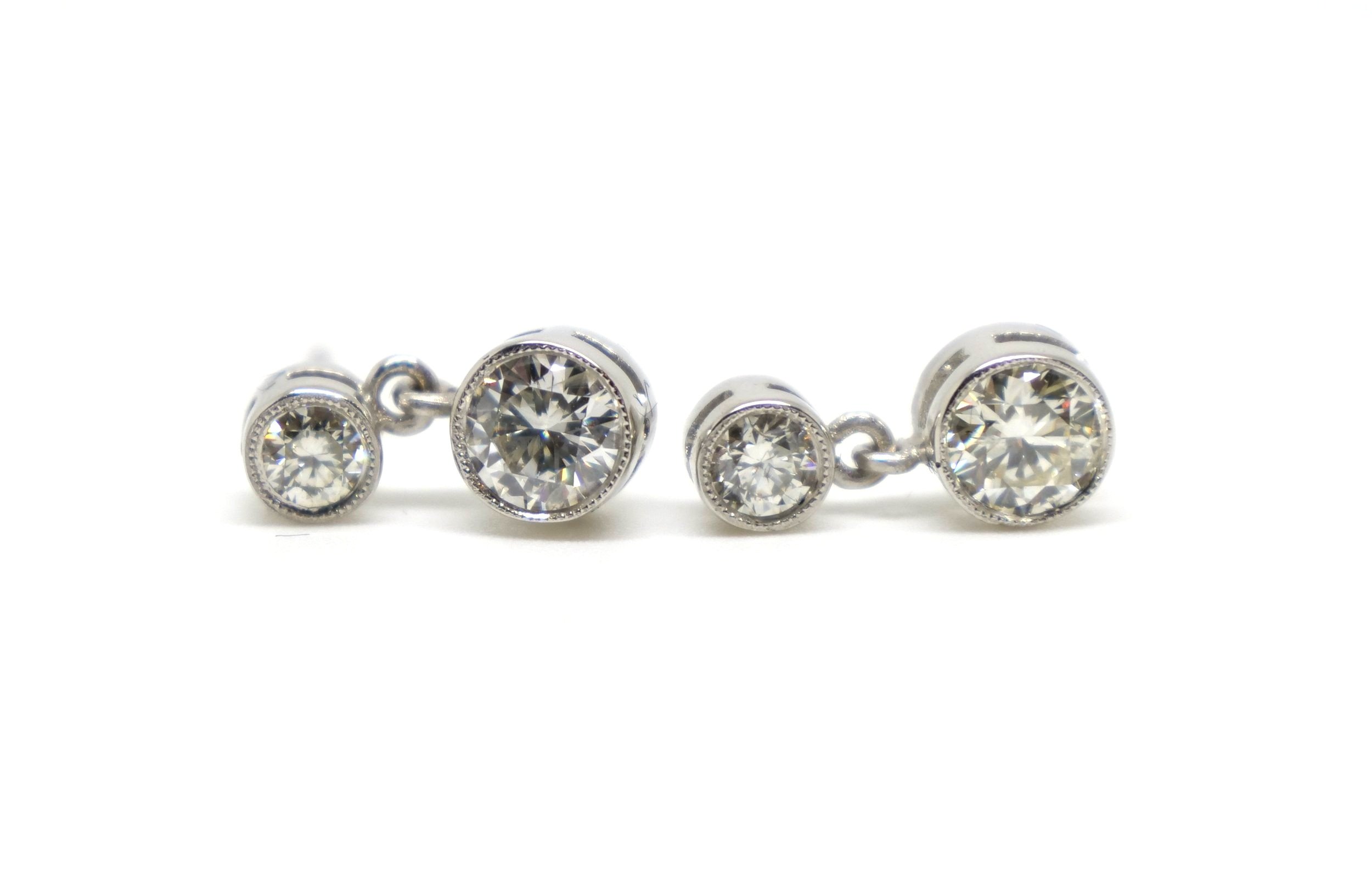 Classic diamond drop stud earrings in a rub over milgrain edged setting. Each earring is set with two brilliant cut diamonds with a total of approximately 0.9cts total.