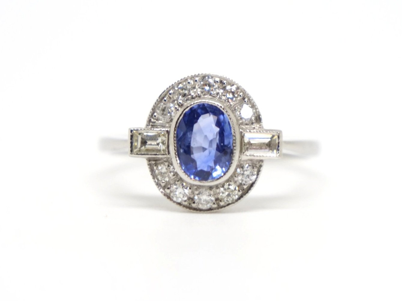 Very pretty Art Deco style platinum sapphire and diamond ring, set with an oval cut sapphire of approximately 1ct, with a baguette cut diamond to each shoulder.