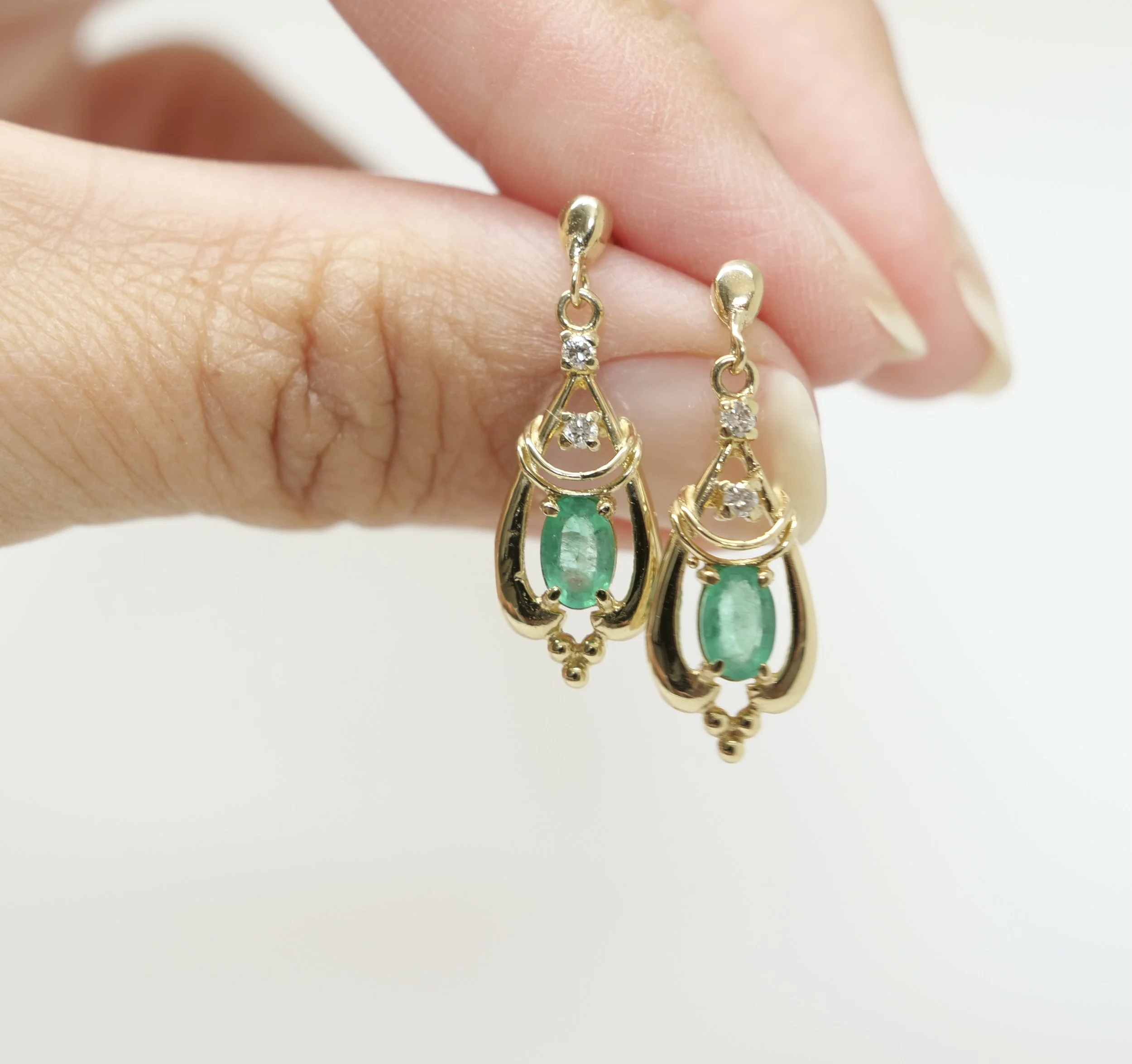Unusual 9ct gold emerald and diamond drop earrings in an Art Noveau style. Set with a central oval cut emerald and a two small diamonds above.