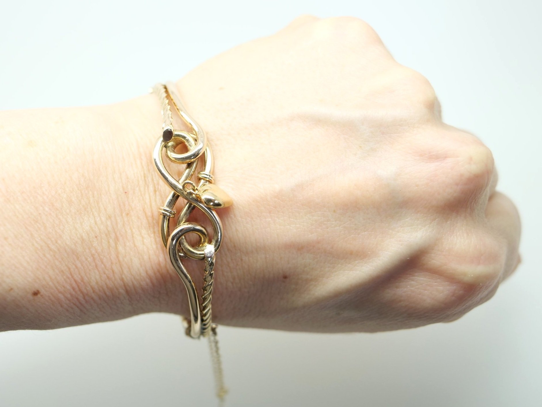 Super vintage bangle in 9ct gold in a wonderful knot style design. Heart charm attached to centre and with safety chain.
