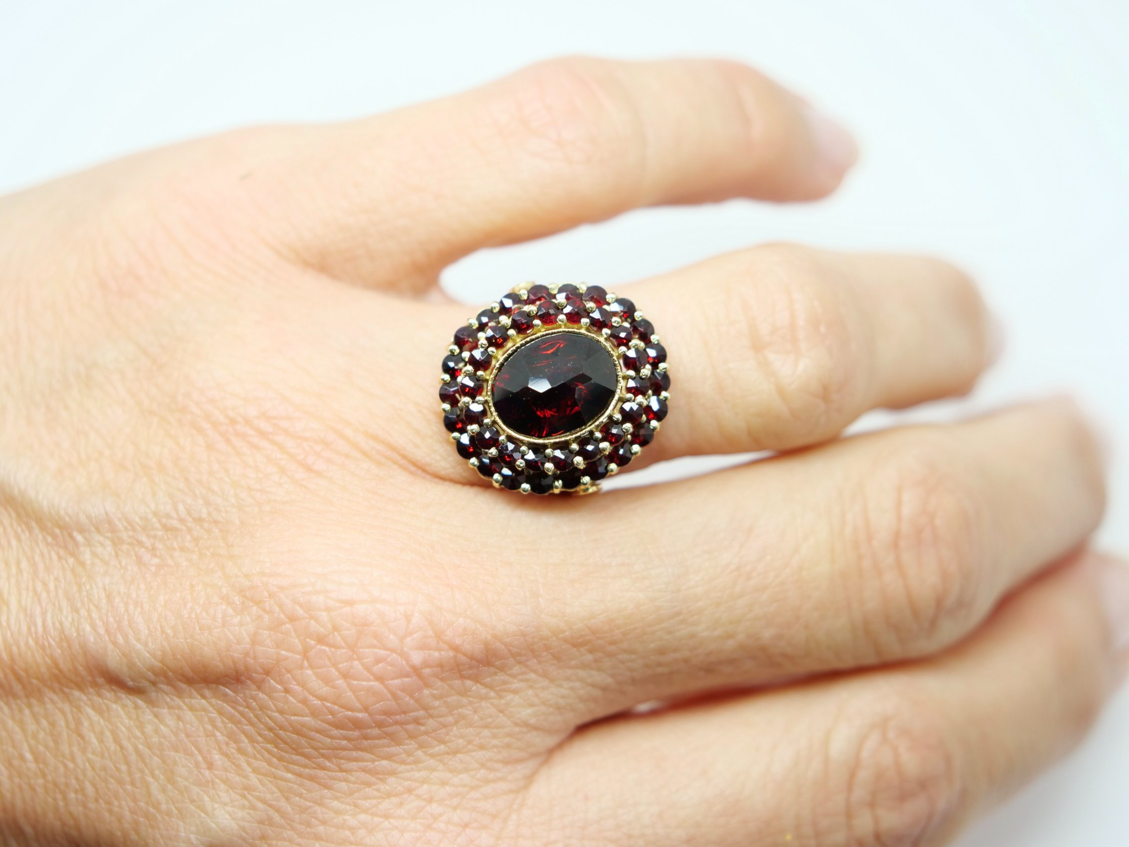 Beautiful 18ct gold garnet cocktail ring, set with an oval cut central garnet and surrounded by two rows of further garnets.