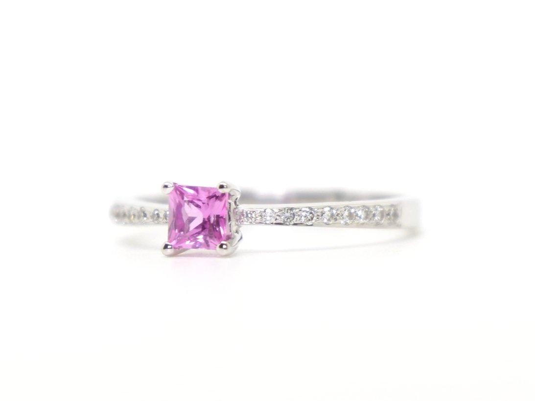 18ct gold pink sapphire and diamond ring, with a central princess cut pink sapphire, and diamonds in shoulders.