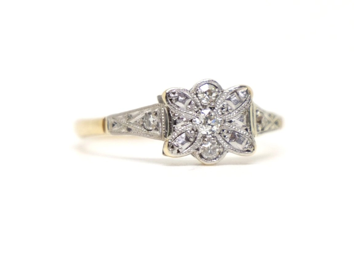 Very pretty 18ct gold Art deco diamond ring, in an unusual floral bow design and set with three small central diamonds. A further diamond set to each shoulder.