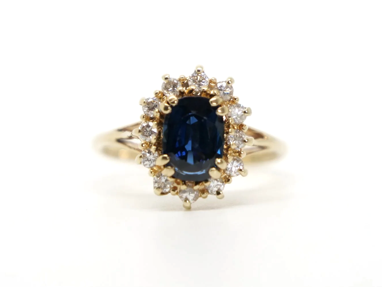 Classic sapphire and diamond cluster ring in 14ct gold, set with an oval cut sapphire of approximately 1.5ct and surrounded by diamonds.