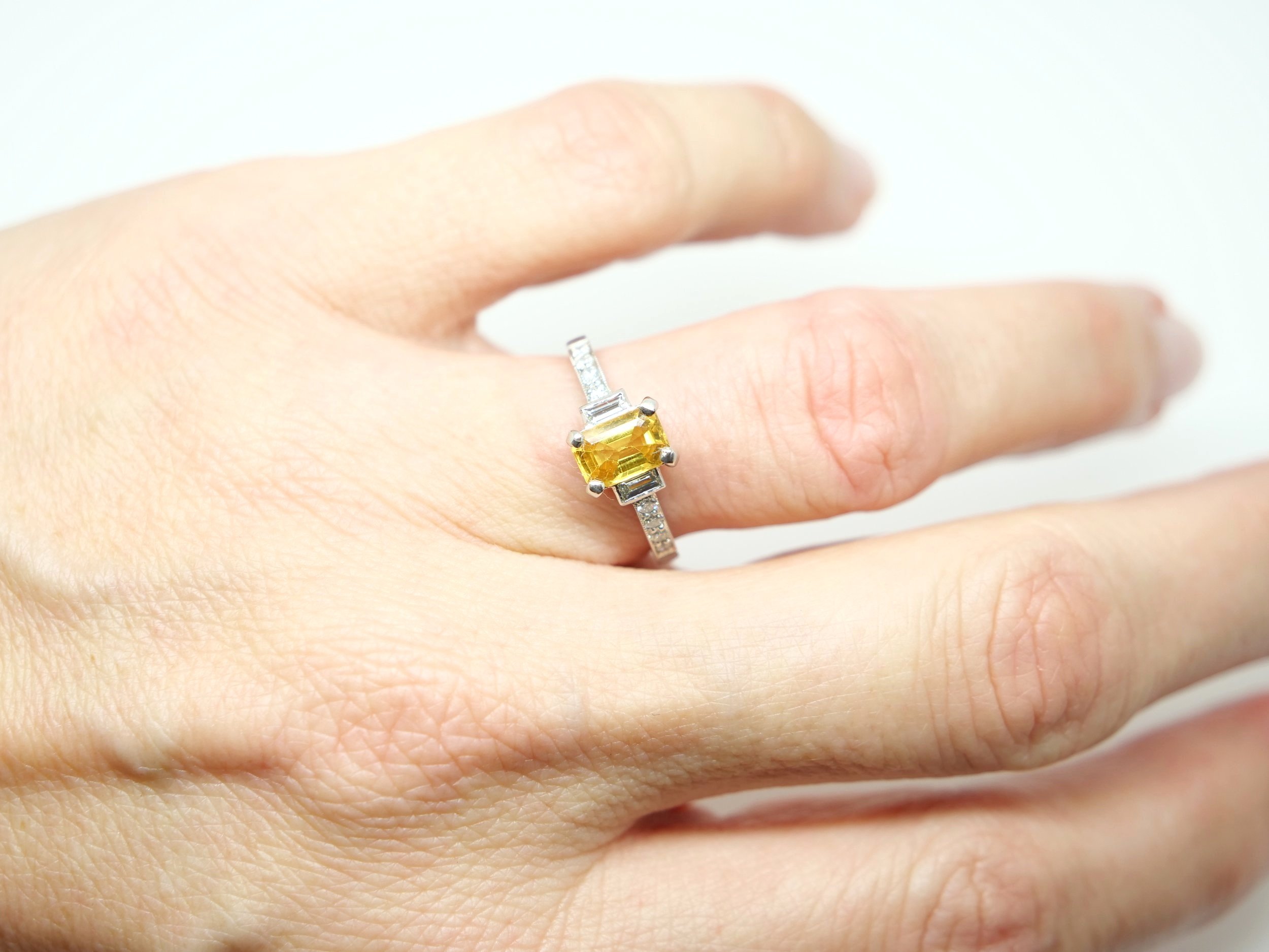 Beautiful vintage style platinum yellow sapphire and diamond ring, set with a 1ct emerald cut sapphire with a baguette cut diamond to each side. Further diamonds to each shoulder.