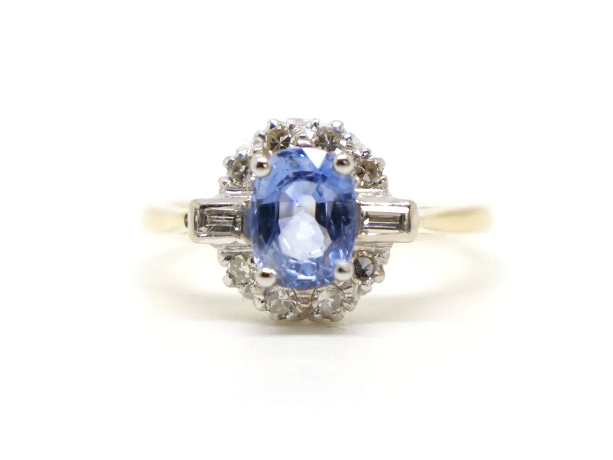 Stunning 18ct gold sapphire and diamond ring, set with an oval light blue sapphire and surrounded by diamonds, with a baguette diamond to each shoulder.