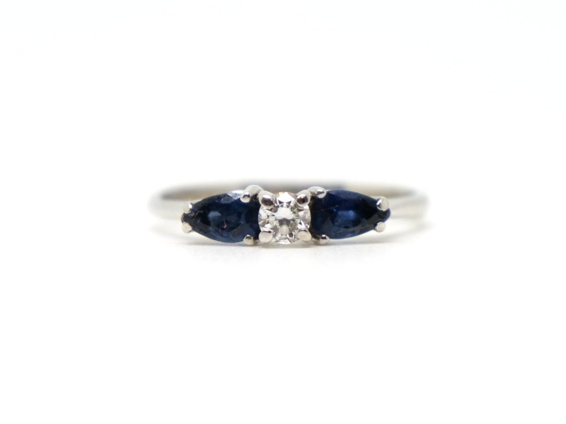 Unusual and elegant 18ct gold sapphire and diamond ring, set with a central brilliant cut diamond, with a pear cut sapphire to each shoulder.