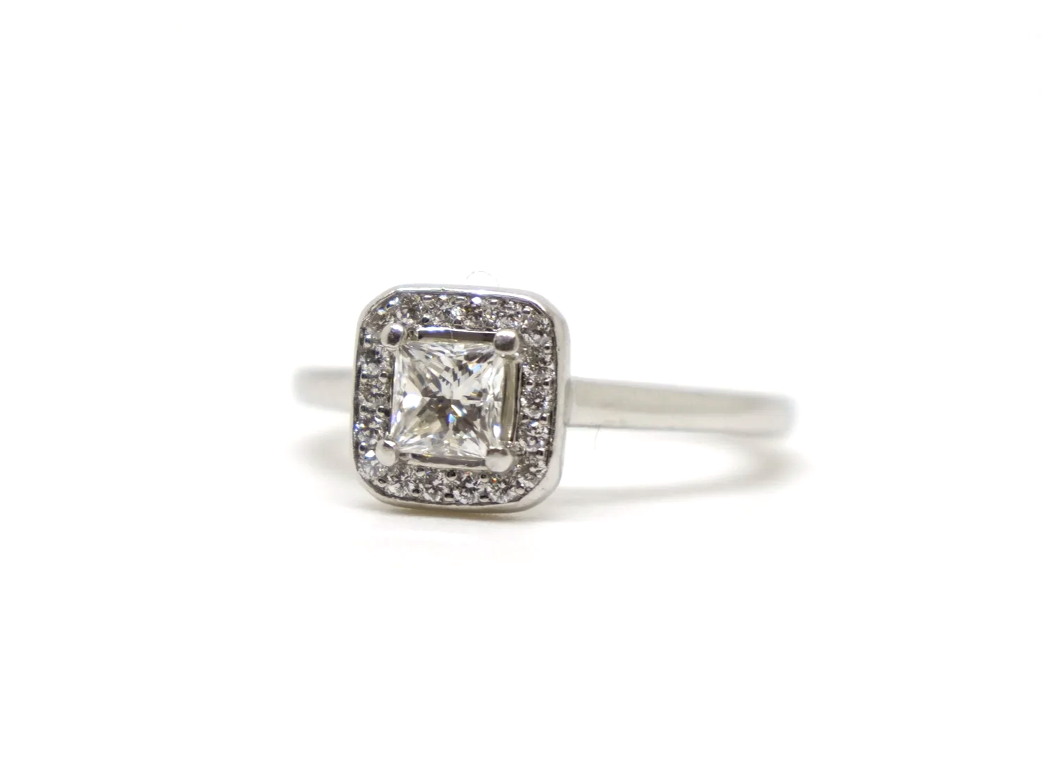 Beautiful platinum diamond ring, set with a central princess cut diamond of excellent quality and surrounded by a halo of diamonds.