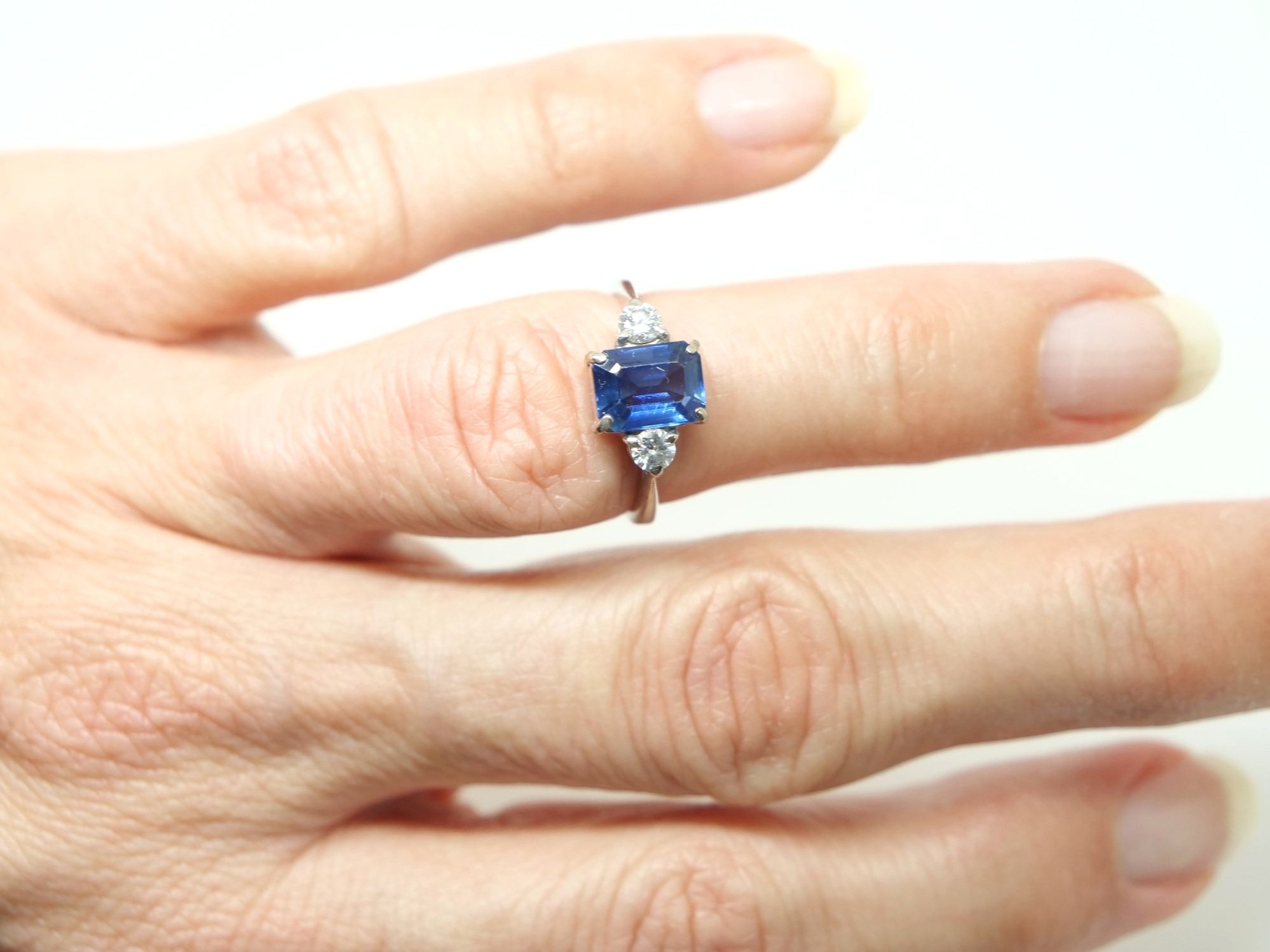 Lovely vintage 18ct gold sapphire and diamond three stone ring, set with a centre emerald cut sapphire of approximately 1.75cts, with a brilliant cut diamond to each side.