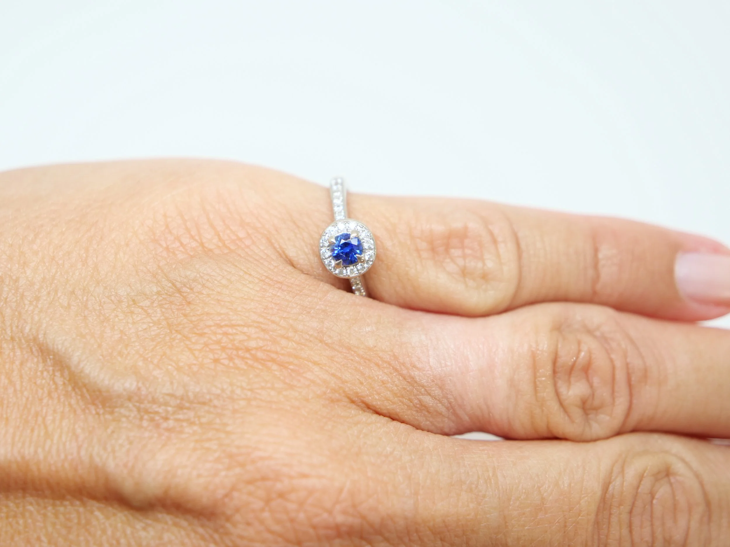Lovely sapphire and diamond halo ring in 18ct white gold, set with a round-cut blue sapphire of approximately 0.35ct, and encircled by a halo of brilliant-cut diamonds