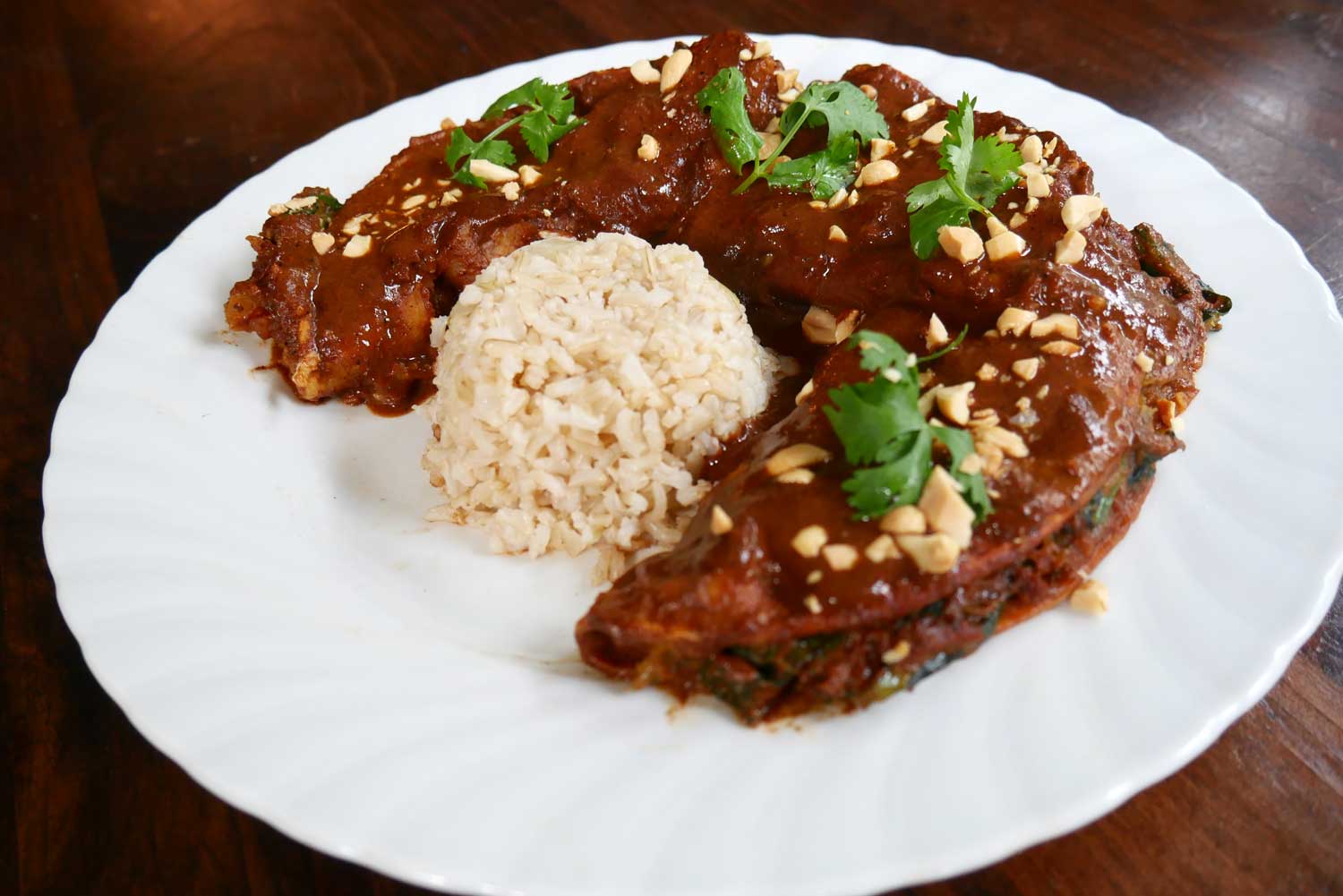 Roasted butternut squash and kale enmoladas with home-made black mole sauce, chopped peanuts and cilantro. Served with brown rice.