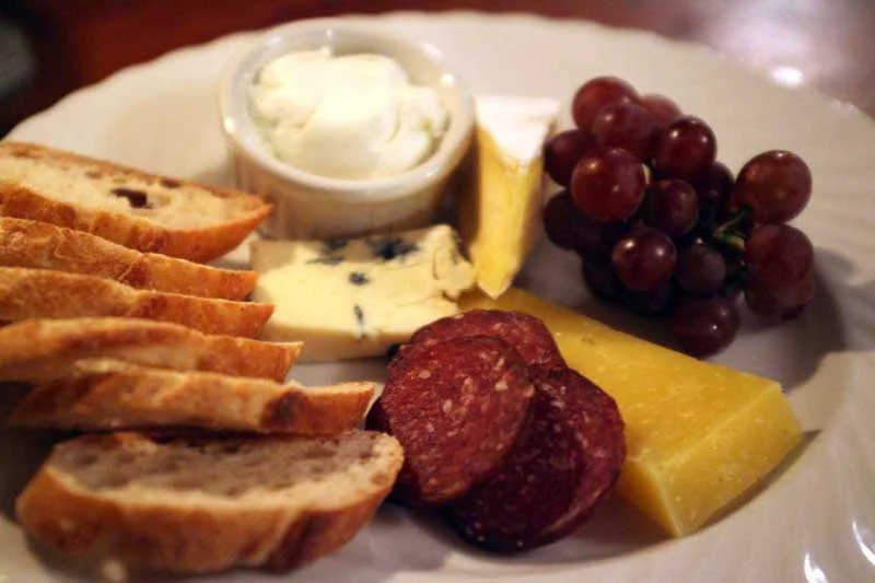 Cheese and charcuterie plate with Sprout Creek Farm , Hawthorne Valley Farm Buttercup Run, Rawson Brook Farm garlic & chive chèvre and venison sausage from Highland Farm and Nostrano Vineyards grapes with sourdough baguette from Berkshire Mountain Bakery .