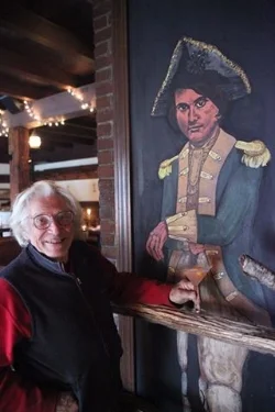 David Rothstein stands with the portrait of Captain Daniel Shays