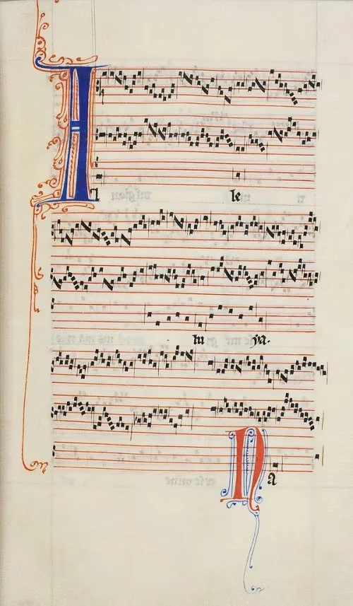A handwritten sheet of musical notation with decorative blue and red initials on a historical manuscript page.