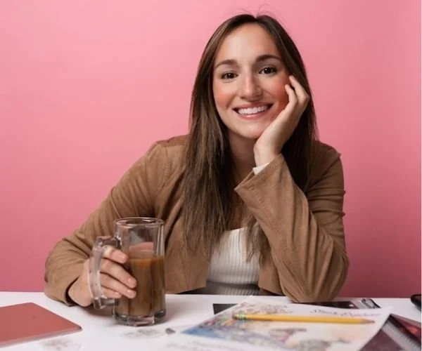 woman sitting at a table with a tall glass of coffee dreaming of the business she wants to open