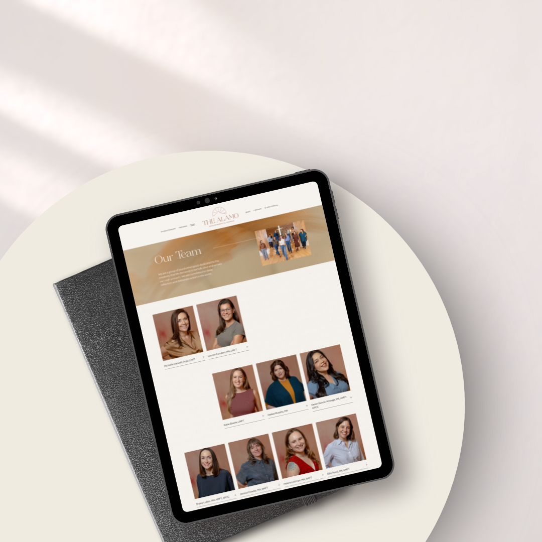 Tablet displaying a team webpage with photos of diverse women and a header titled "Our Team" on a white circular table with a textured black cover.