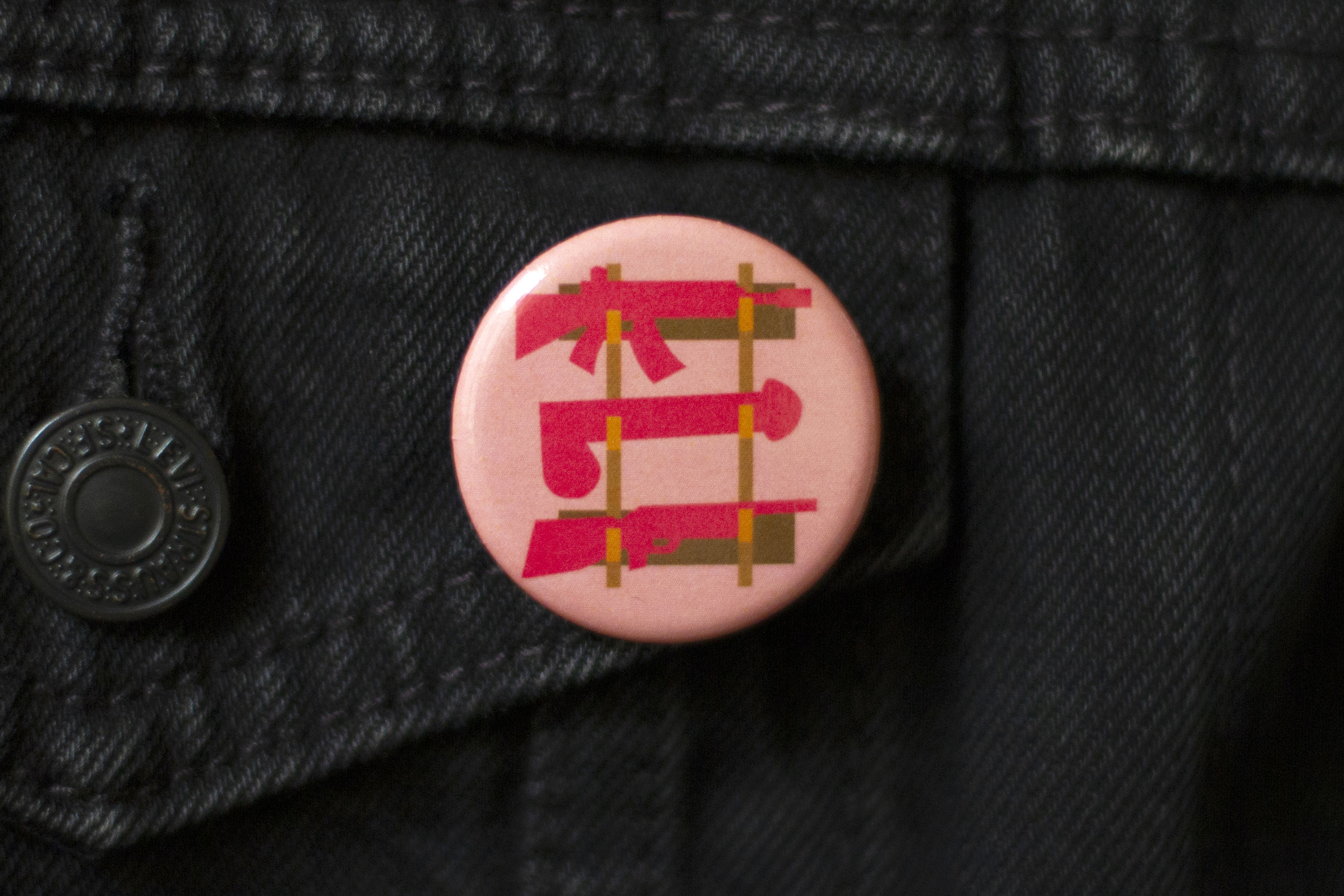 Implied Threat art button by CockBloq pinned on a denim jacket