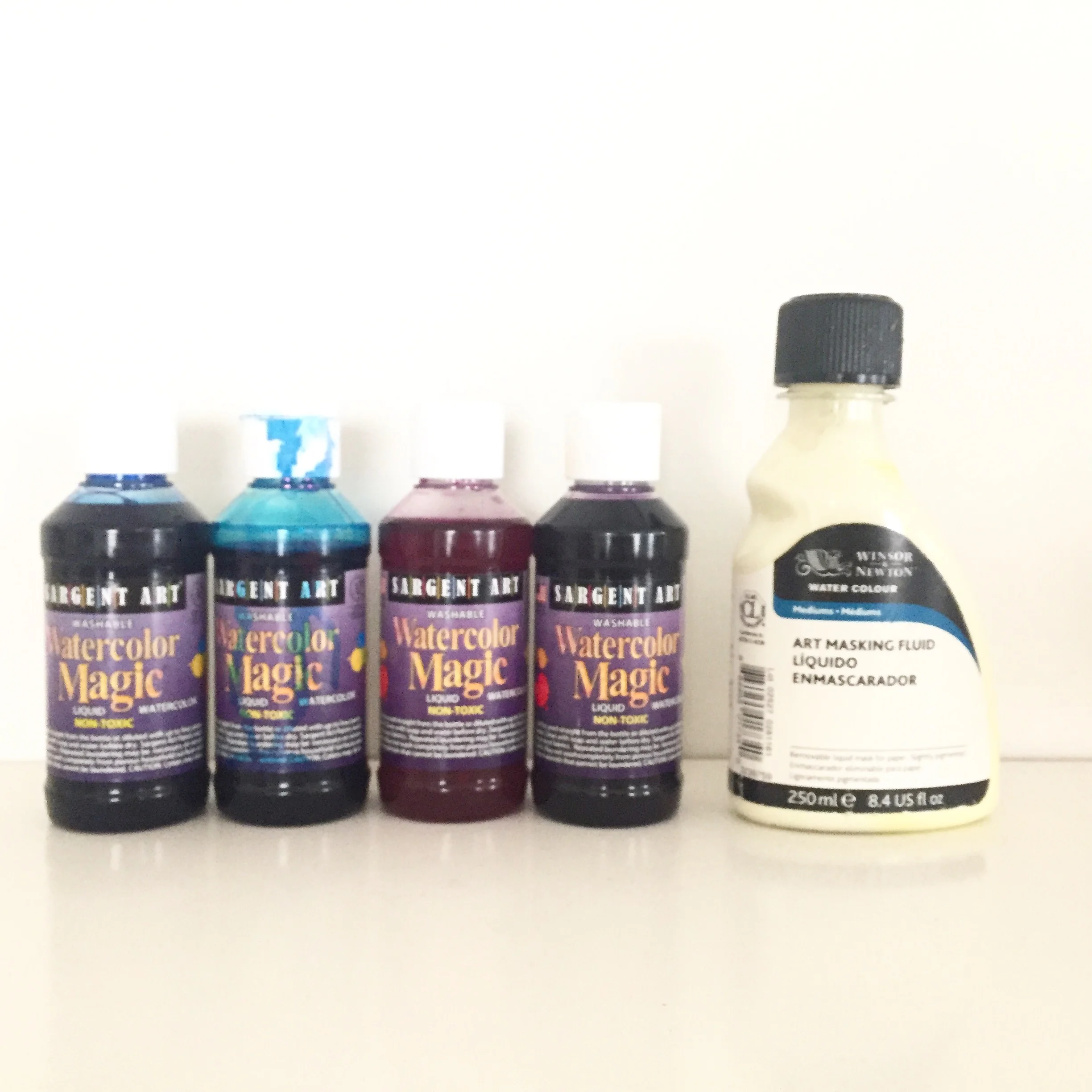 Liquid watercolors and art masking fluid shown side by side.