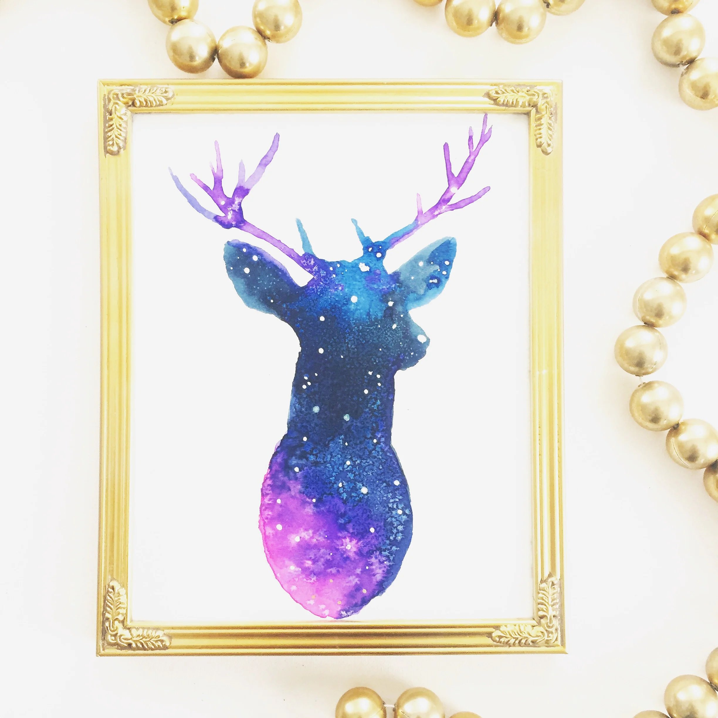 Galaxy Reindeer in gold picture frame with gold decorative beads.