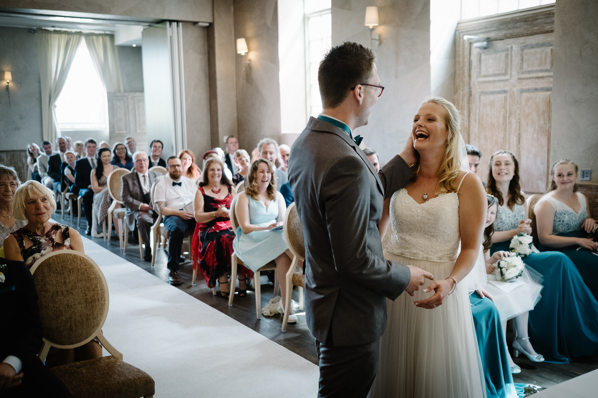 A bride and groom smiling in their wedding ceremony at Fawsley Hall, Northamptonshire